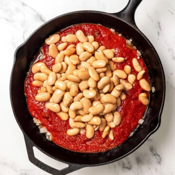 Butter beans and marinara added to cast iron skillet.
