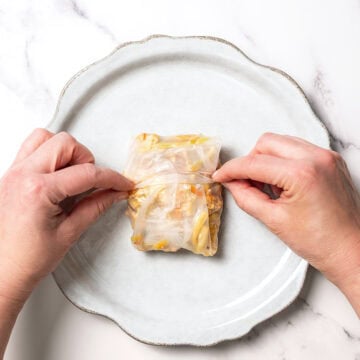 Folding rice paper dumpling on plate.