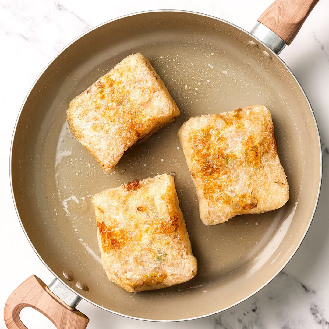 These vegan rice paper dumplings are crispy on the outside, chewy around the edges, with a savory cabbage and tofu filling. Viral on TikTok! Vegan rice paper dumplings in pan.