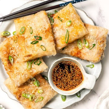Crispy rice paper dumplings on plate with dipping sauce.