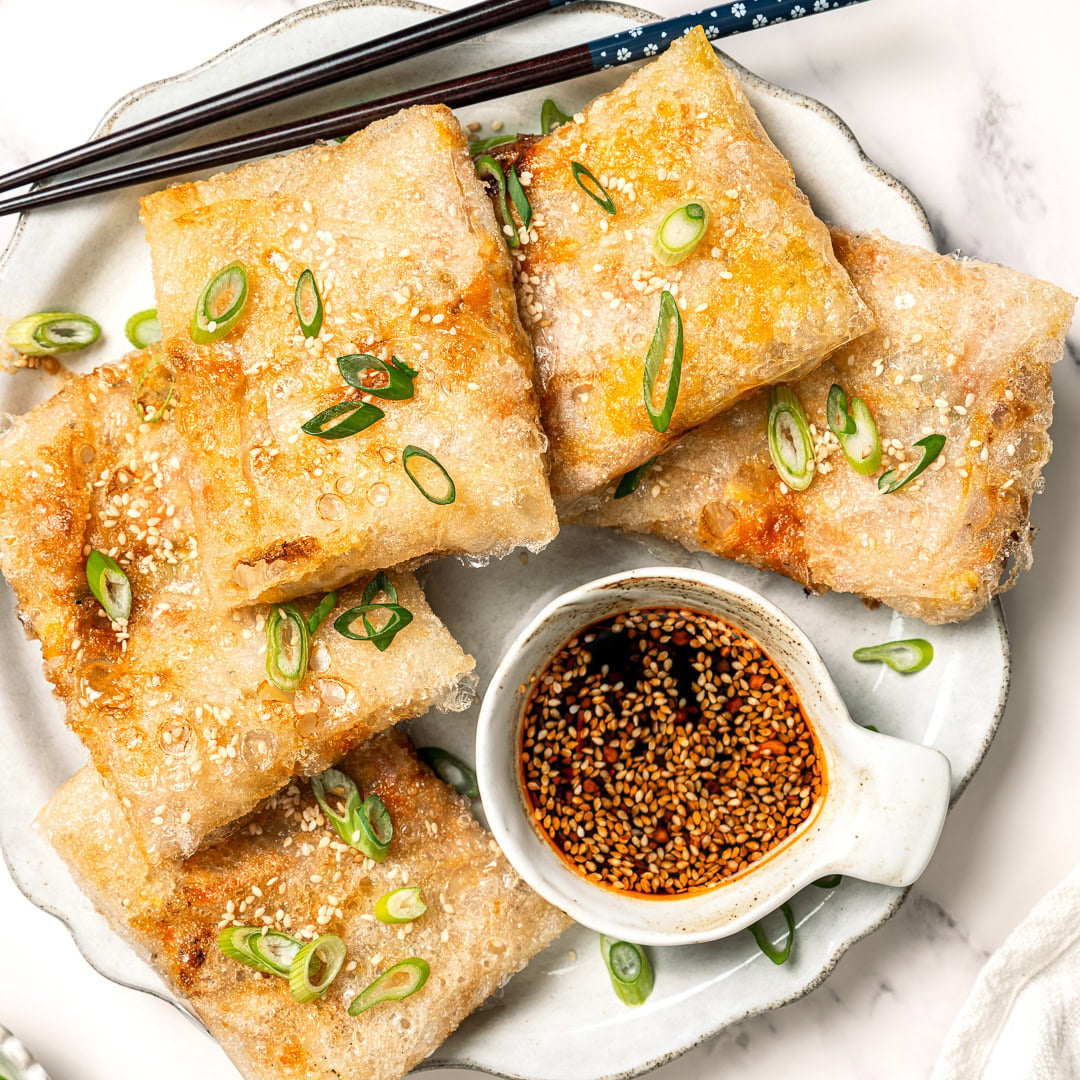 These vegan rice paper dumplings are crispy on the outside, chewy around the edges, with a savory cabbage and tofu filling. Viral on TikTok! Crispy rice paper dumplings on plate with dipping sauce.