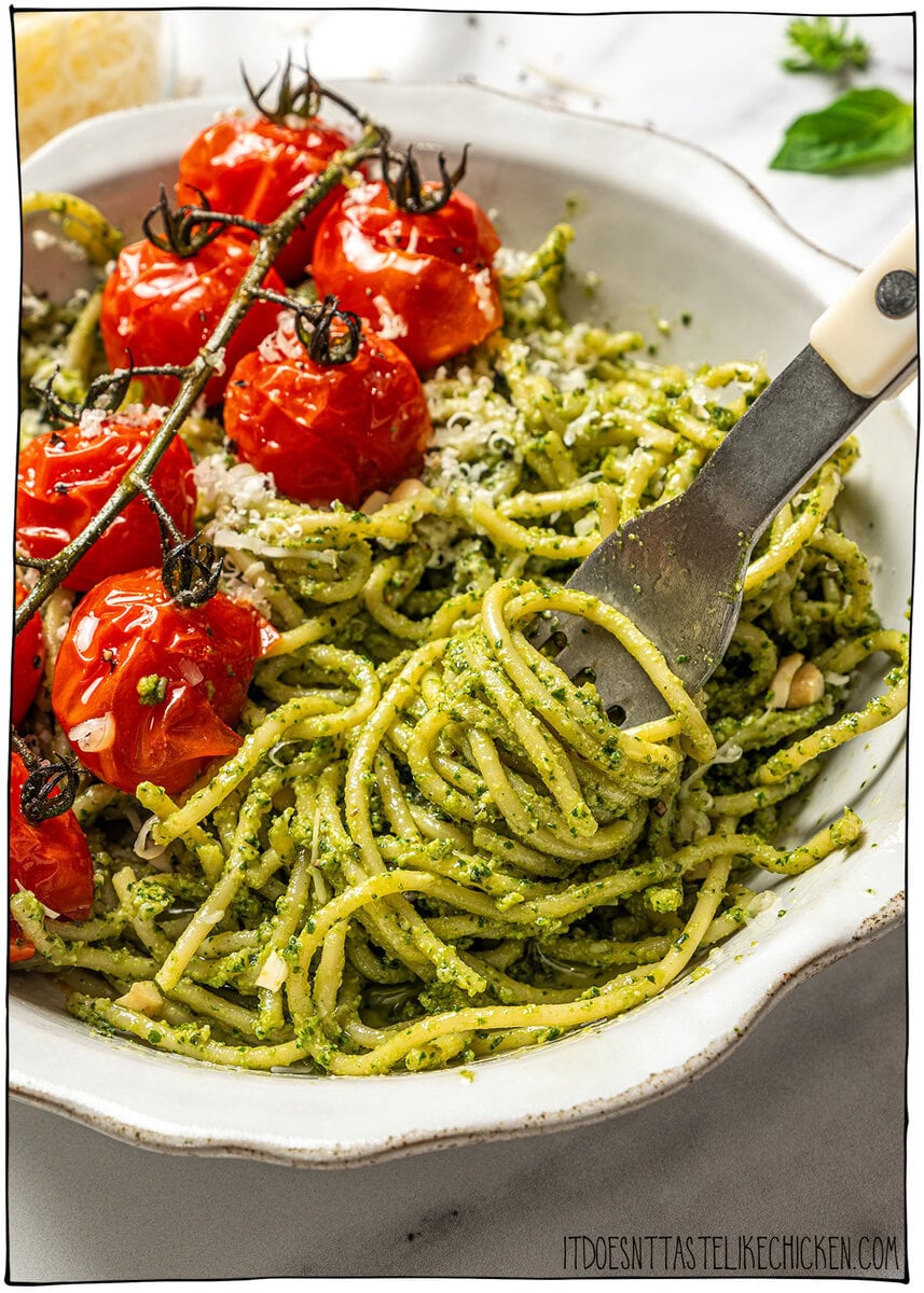 This creamy vegan pesto is rich, vibrant, and packed with fresh basil flavor, just like classic pesto, but completely dairy-free! Fork swirling in vegan pesto pasta in bowl with roasted cherry tomatoes.