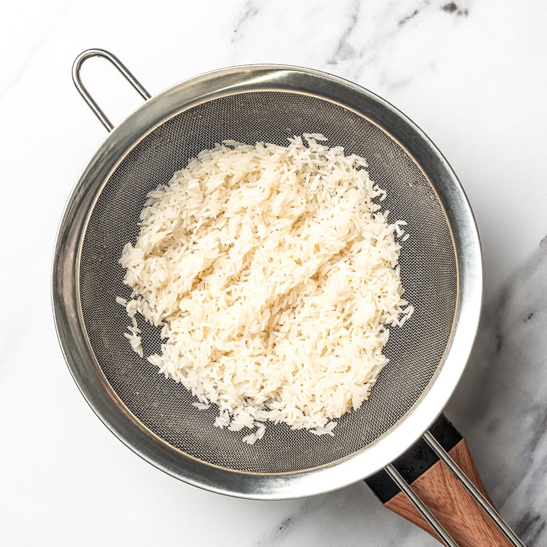 This easy Chipotle rice recipe is fluffy, lightly seasoned, and finished with fresh lime juice and cilantro for that signature fresh flavor! Rice in colander.