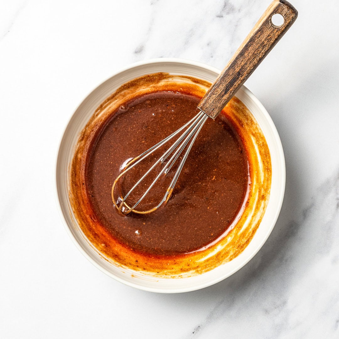 Pad thai sauce in bowl with whisk.