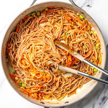 Sauce and noodles added to pan with vegetables for pad thai.