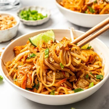 Bowl of pad thai noodles wound around chopsticks.