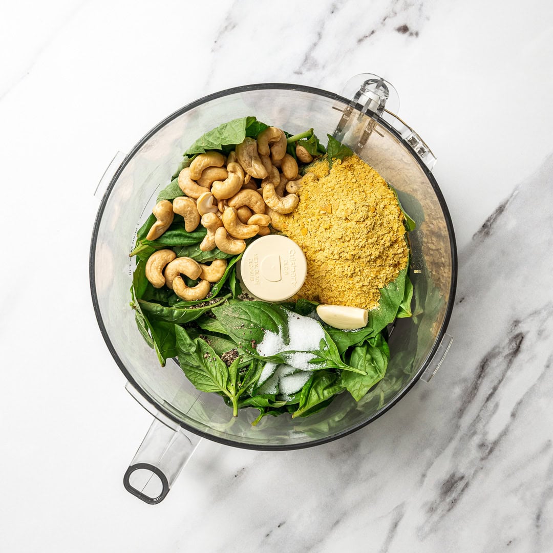 This creamy vegan pesto is rich, vibrant, and packed with fresh basil flavor, just like classic pesto, but completely dairy-free! Ingredients for vegan pesto recipe in food processor.
