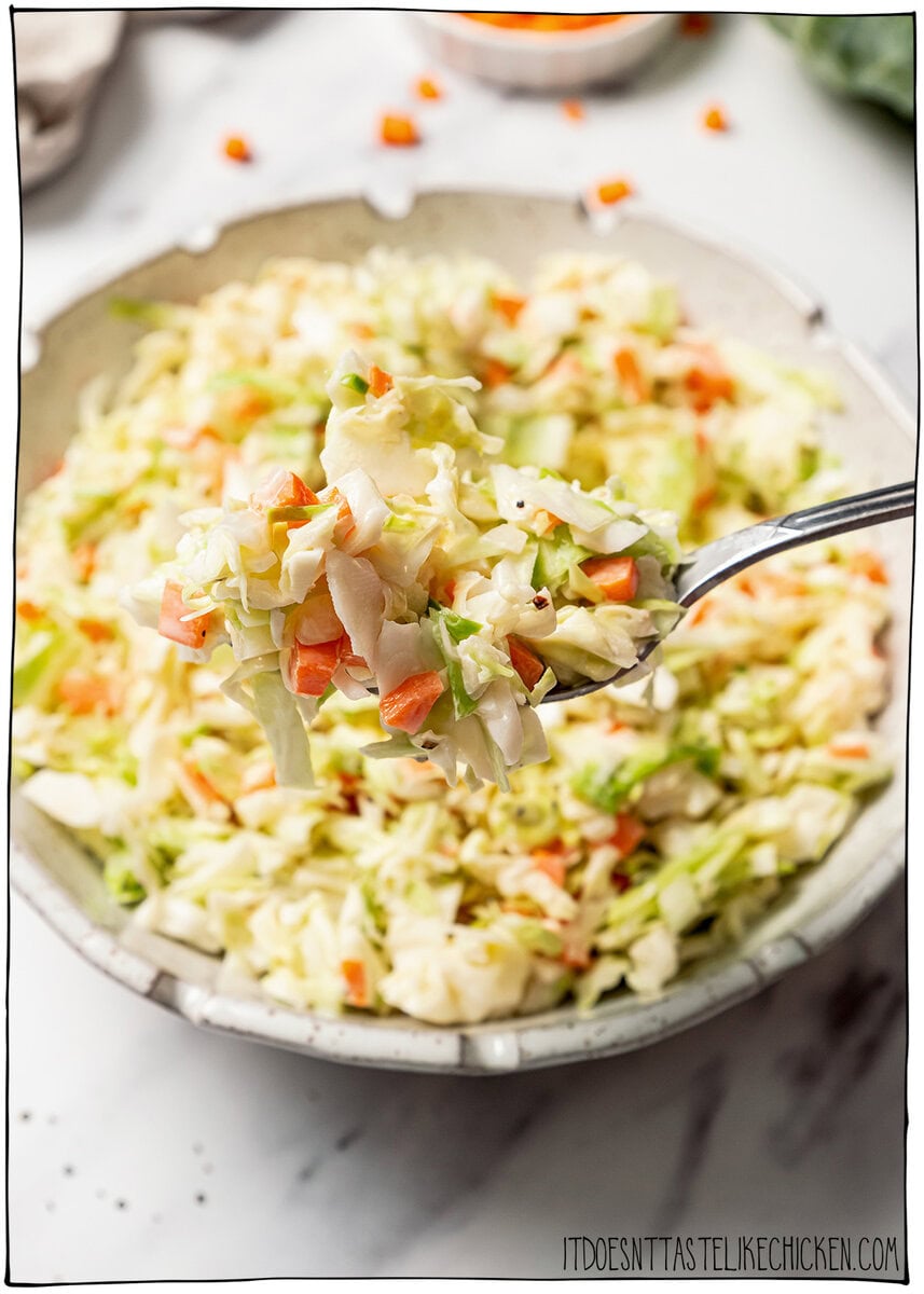 This KFC coleslaw copycat is creamy, tangy, and perfectly sweet with that classic flavor everyone loves. Easy to make with vegan mayo! Spoonful of KFC coleslaw held over bowl.