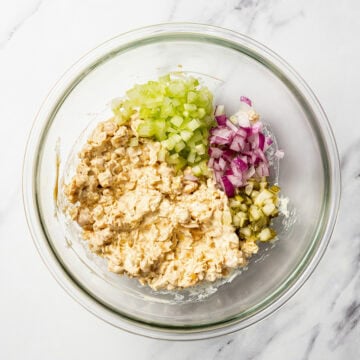 Celery, red onion, and pickle added to bowl of chickpea salad.