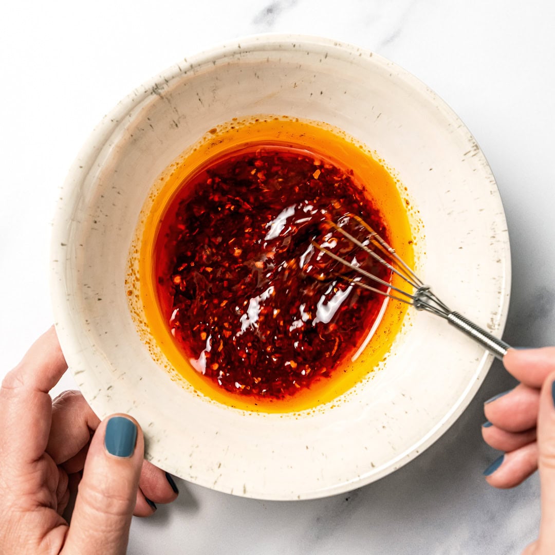 Whisking chili sauce in bowl.