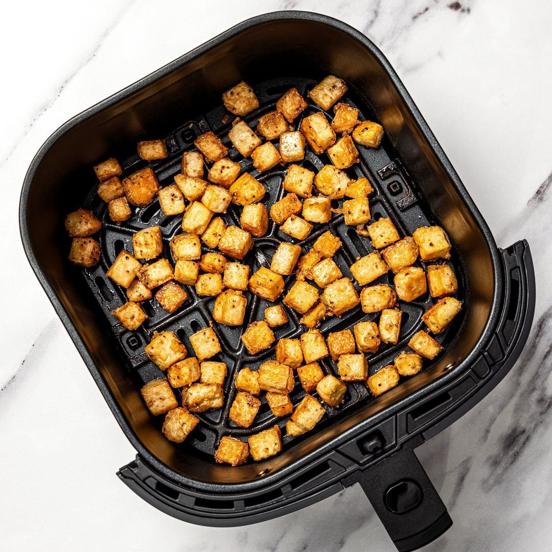 Whether you pan-fry, bake, or use an air fryer, this easy crispy tofu recipe turns out golden, flavorful, and delicious every single time! Crispy tofu in air fryer basket.