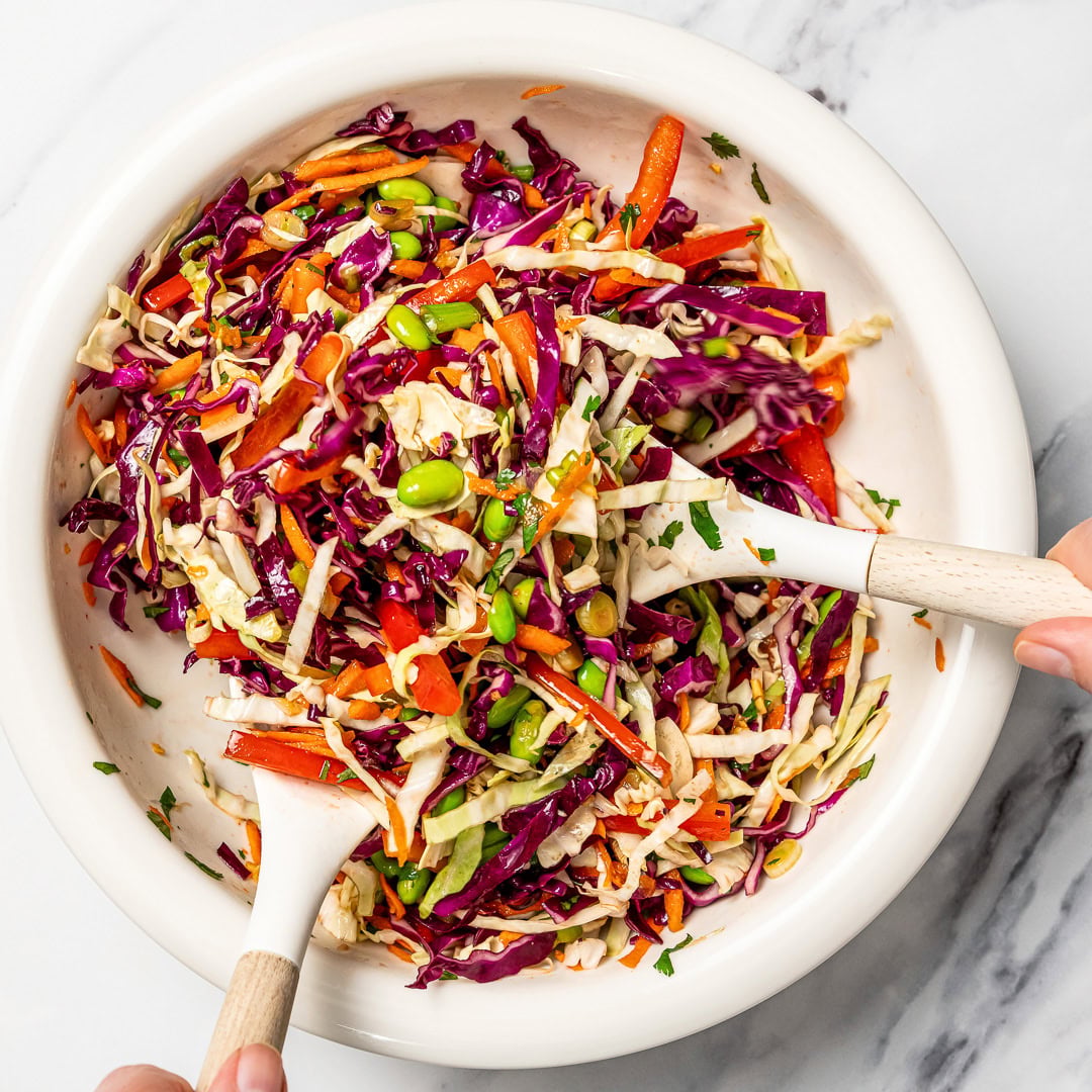 Tossing crunchy sesame cabbage salad in bowl.