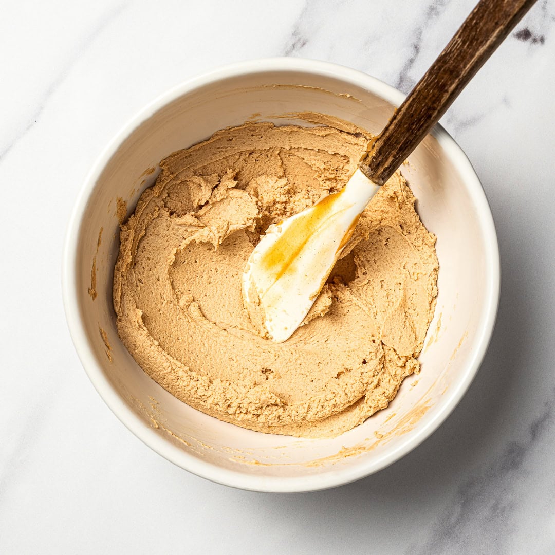 This easy dog birthday cake recipe is soft, simple and made with wholesome, dog-friendly ingredients like banana, oats and peanut butter! Peanut butter frosting in bowl.