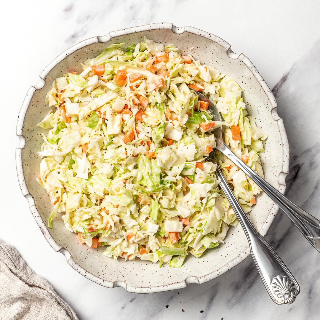 This KFC coleslaw copycat is creamy, tangy, and perfectly sweet with that classic flavor everyone loves. Easy to make with vegan mayo! Bowl of KFC coleslaw with two spoons.