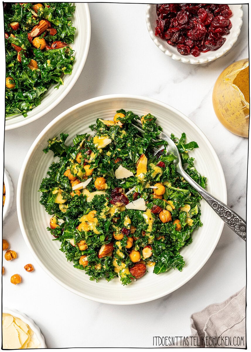 With shredded kale, zippy lemon dressing, dried cranberries, almonds and crispy chickpeas, this easy kale salad recipe is the best ever! Bowl of kale salad with chickpeas, almonds, cranberries, and vegan Parmesan.