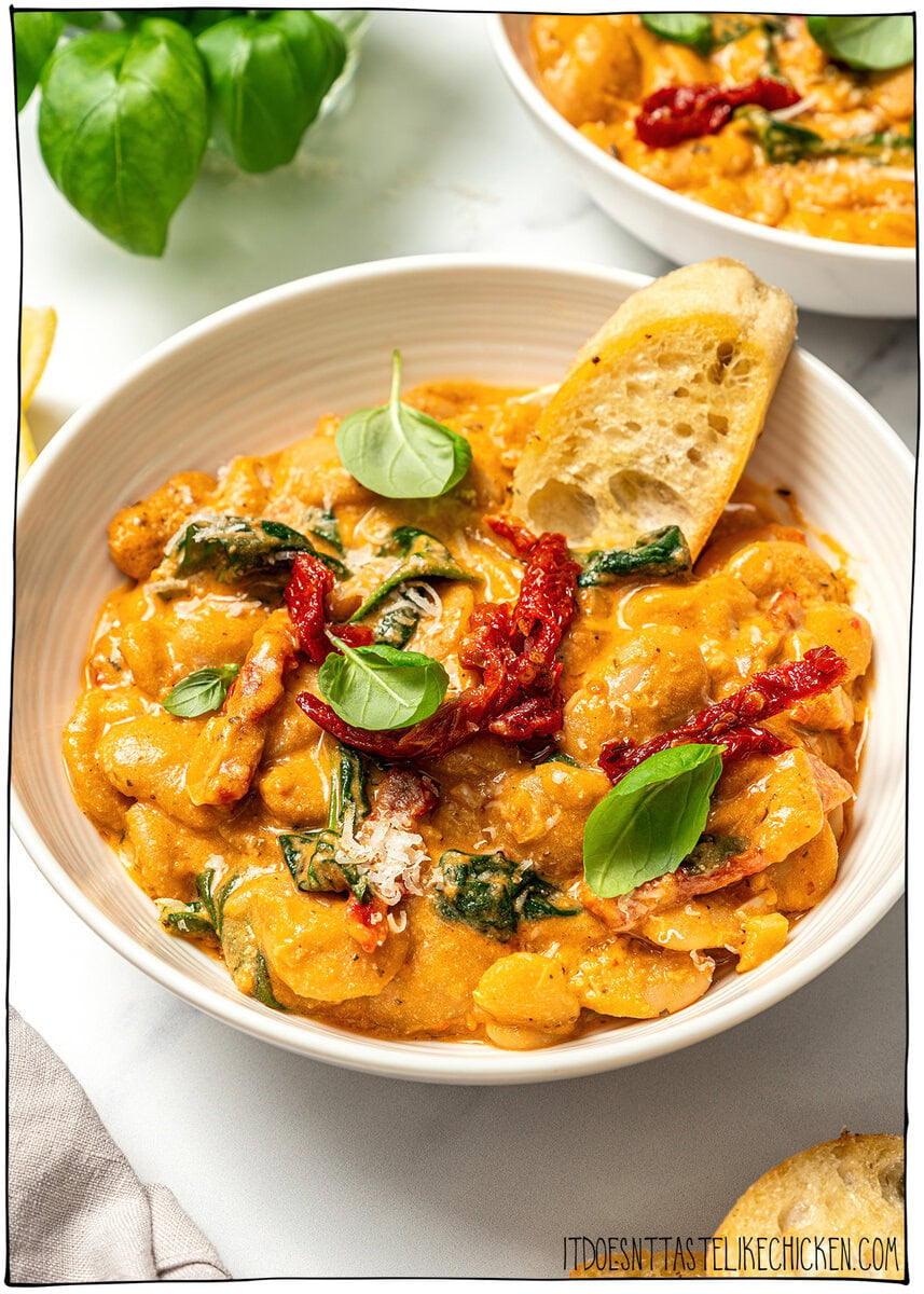 Marry me butter beans are an easy one-pan vegan dinner recipe with a creamy sun-dried tomato garlic sauce that tastes restaurant-worthy! Bowl of marry me butter beans with slice of bread.
