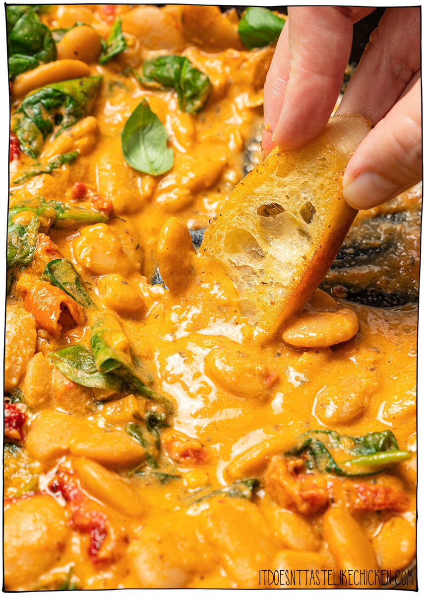 Marry me butter beans are an easy one-pan vegan dinner recipe with a creamy sun-dried tomato garlic sauce that tastes restaurant-worthy! Dipping bread into marry me butter beans.