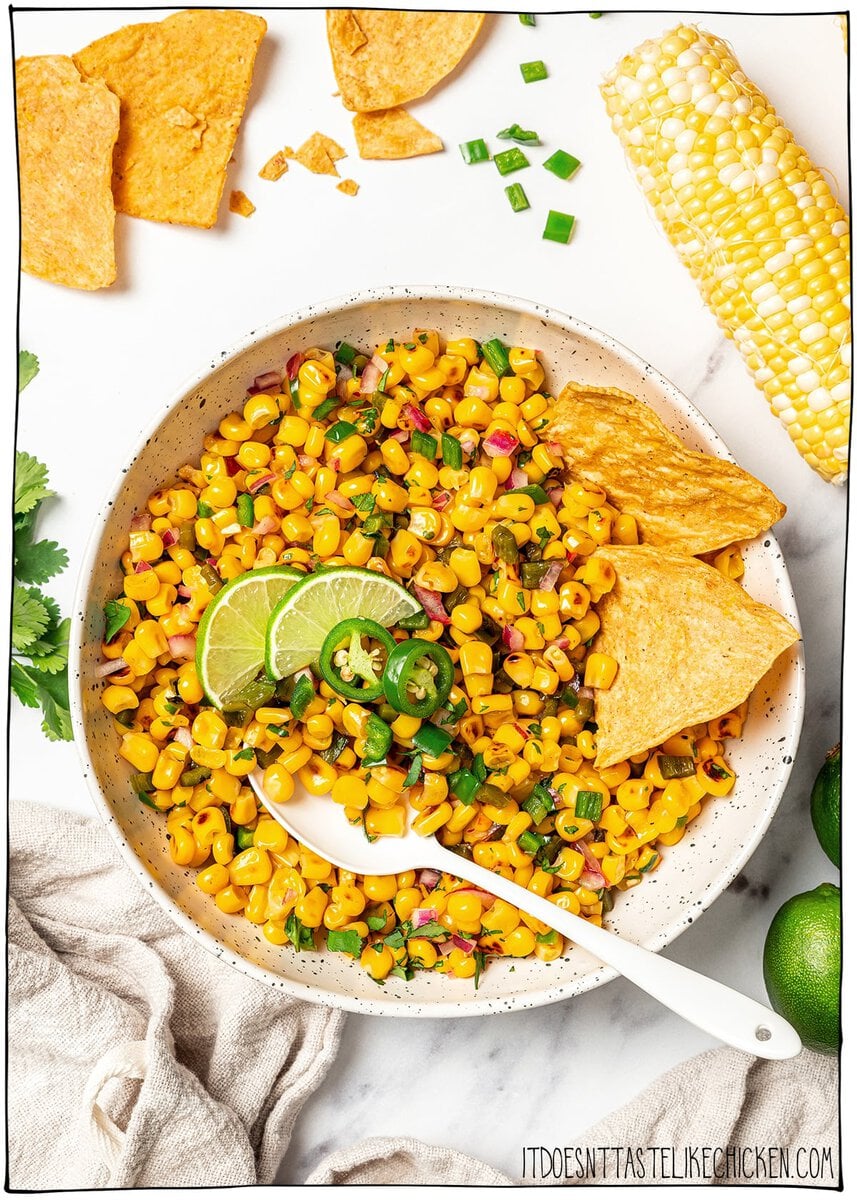 Made with charred corn, roasted poblano, cilantro, lime and red onion, this copycat Chipotle corn salsa is bright, smoky and so delicious! Bowl of corn salsa with spoon and tortilla chips.