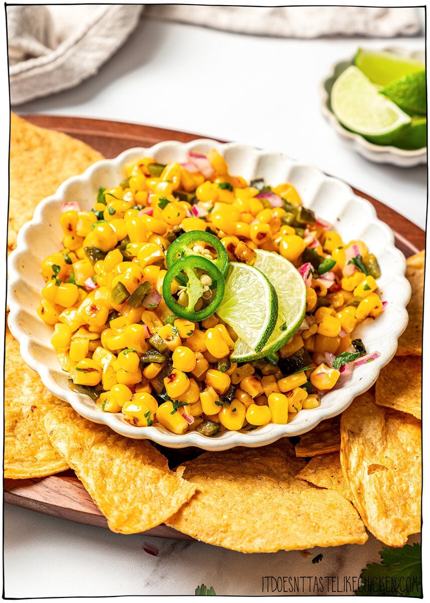 Made with charred corn, roasted poblano, cilantro, lime and red onion, this copycat Chipotle corn salsa is bright, smoky and so delicious! Bowl of corn salsa set on tray with tortilla chips.