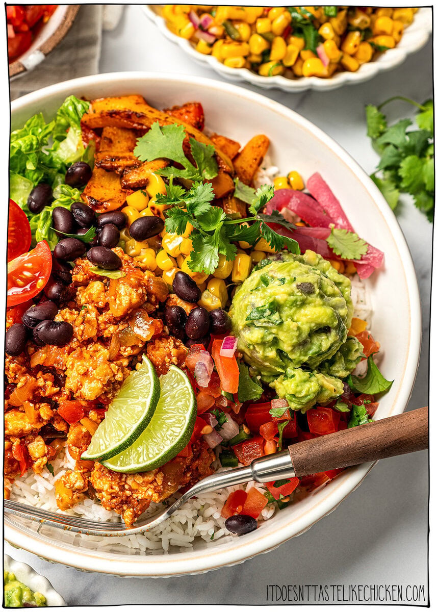 A guide to building your own burrito bowl with rice, protein, veggies, salsa, and creamy toppings for an easy and satisfying vegan meal. Fork in vegan burrito bowl.