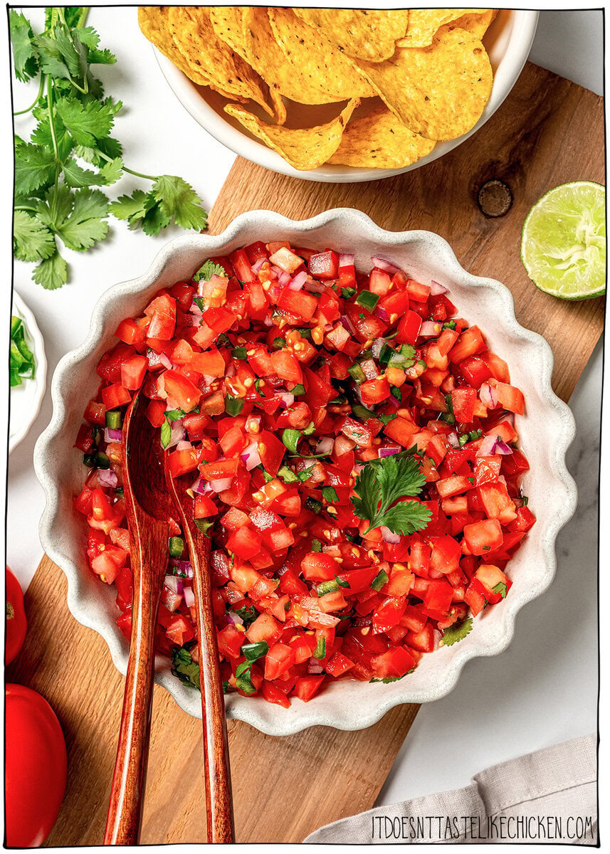 This pico de gallo tastes just like Chipotle's, but even better because it’s extra fresh, easy to customize, and made at home in minutes! Bowl of pico de gallo with two wooden spoons.