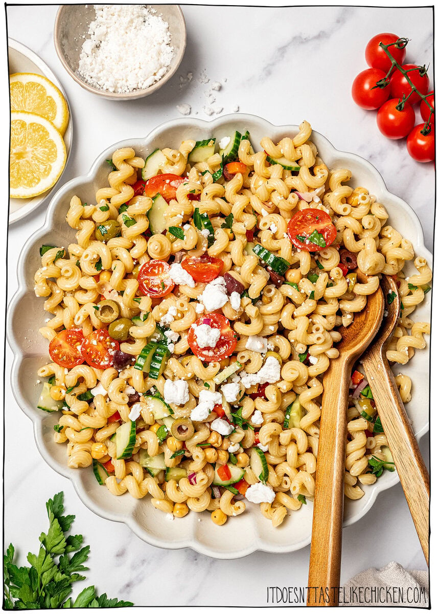 Bowl of pasta salad with text overlay that reads Mediterranean chickpea pasta salad. Mediterranean chickpea pasta salad in serving dish.
