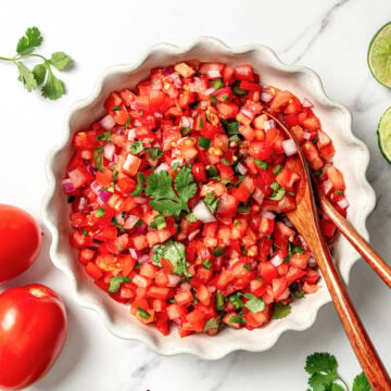 Bowl of pico de gallo with two wooden spoons.