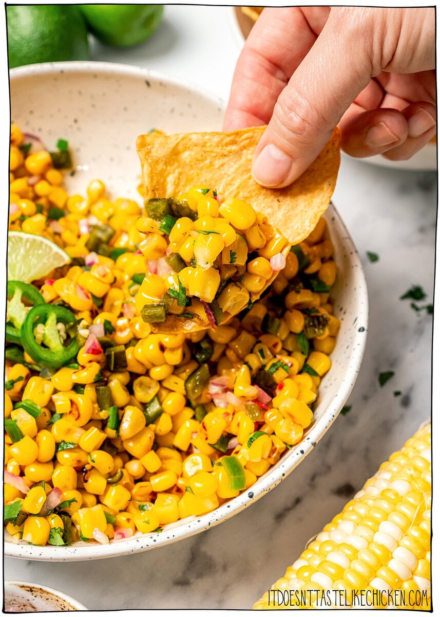 Made with charred corn, roasted poblano, cilantro, lime and red onion, this copycat Chipotle corn salsa is bright, smoky and so delicious! Dipping chip into corn salsa.