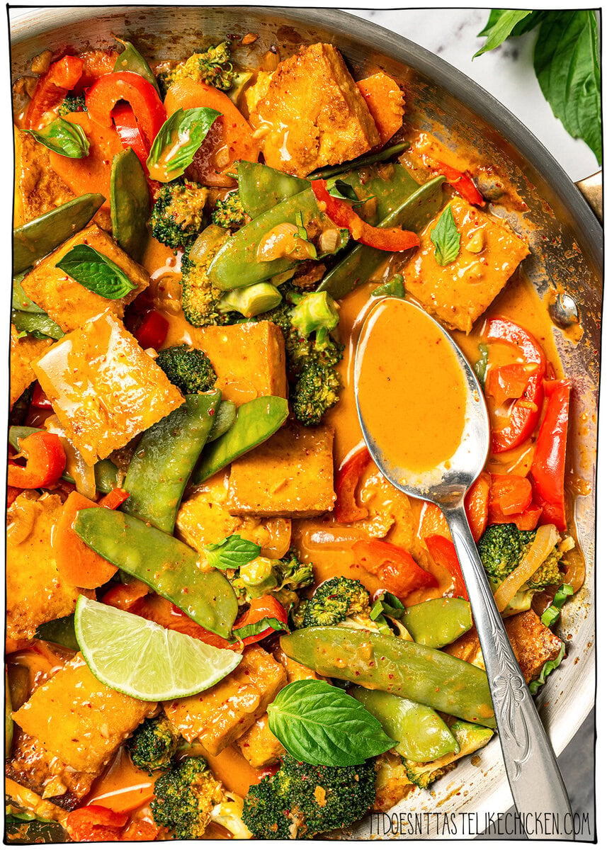 This easy vegan Thai red curry is creamy, cozy and packed with tender veggies and tofu in a rich coconut curry sauce. Perfect for busy days! Spoon in skillet of vegan Thai red curry.