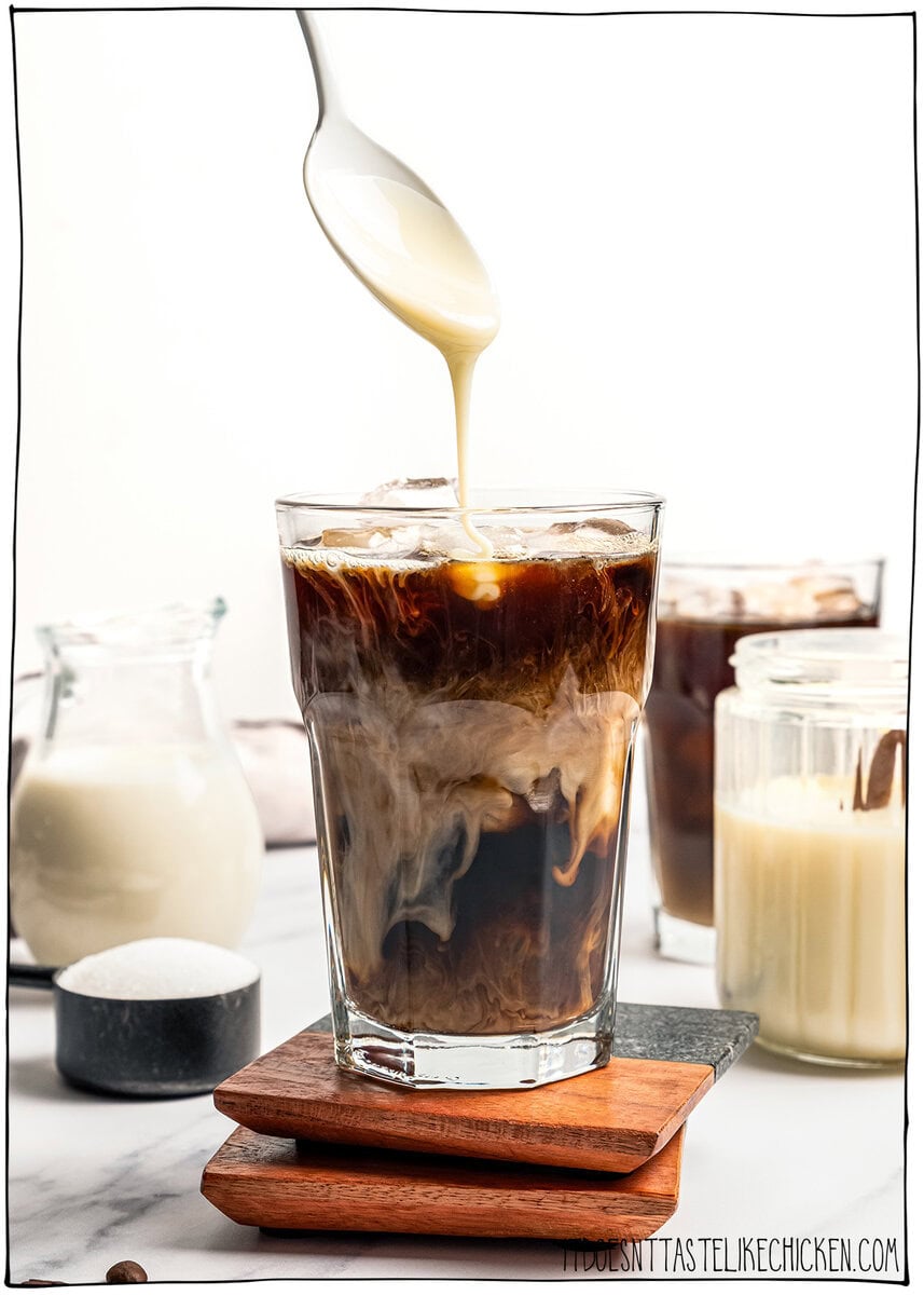 Spooning vegan sweetened condensed milk into iced coffee.