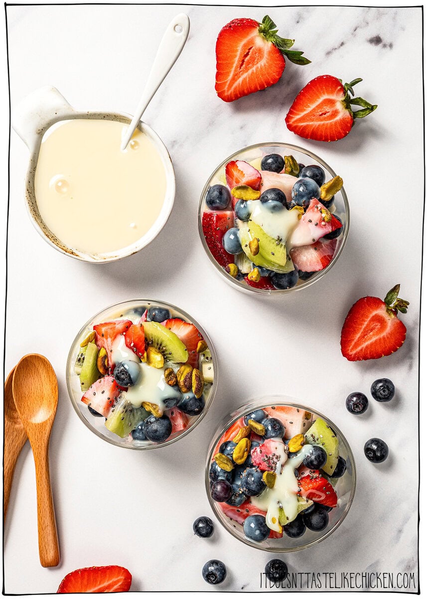 This easy vegan sweetened condensed milk is thick and creamy, perfect for using in dairy-free desserts and drinks. Just 2 ingredients! Three bowls of fruit salad with bowl of vegan sweetened condensed milk.