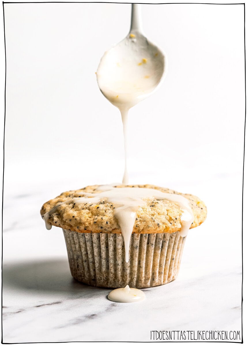 Spoon drizzling glaze onto vegan lemon poppy seed muffin.