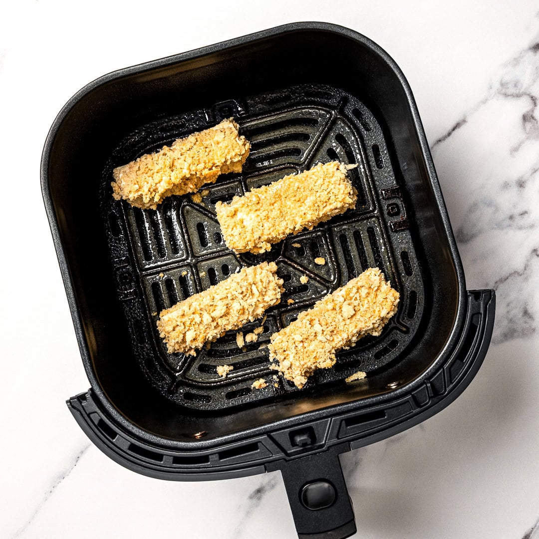 Plate of tofu chicken with sauce, with text overlay that reads vegan chicken fingers. Tofu chicken fingers in air fryer.
