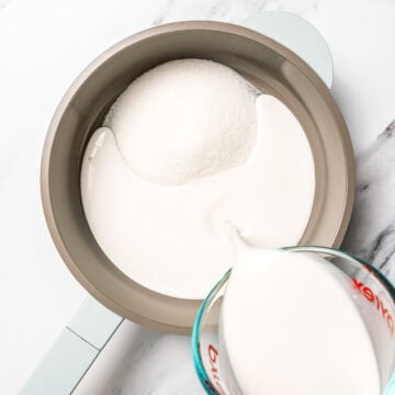 Pouring coconut milk into pan with sugar.
