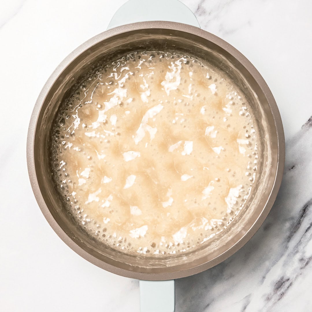 This easy vegan sweetened condensed milk is thick and creamy, perfect for using in dairy-free desserts and drinks. Just 2 ingredients! Vegan sweetened condensed milk simmering in pan.