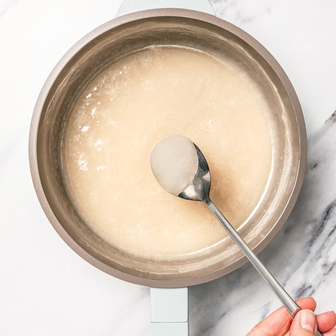 This easy vegan sweetened condensed milk is thick and creamy, perfect for using in dairy-free desserts and drinks. Just 2 ingredients! Spoon in pan of vegan sweetened condensed milk.