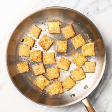 Tofu cubes cooking in skillet.
