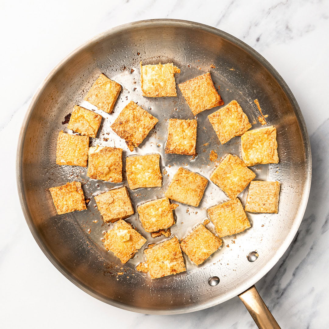 This easy vegan Thai red curry is creamy, cozy and packed with tender veggies and tofu in a rich coconut curry sauce. Perfect for busy days! Tofu cubes cooking in skillet.
