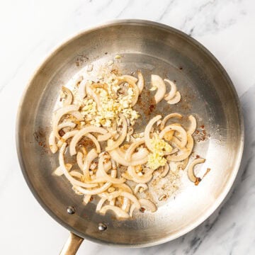 Garlic, ginger, and onions cooking in skillet.