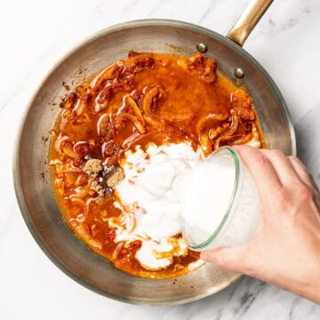 Pouring coconut milk into pan for curry.