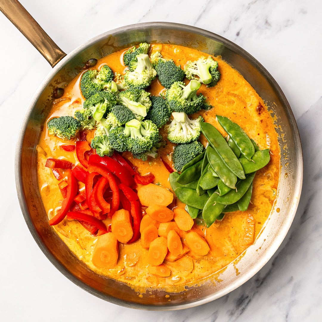 This easy vegan Thai red curry is creamy, cozy and packed with tender veggies and tofu in a rich coconut curry sauce. Perfect for busy days! Vegetables added to pan of red curry sauce.