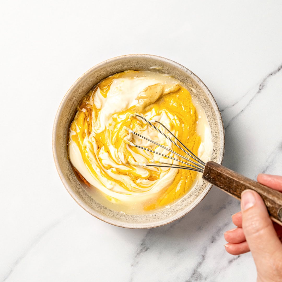 This homemade Vegan Honey Mustard Sauce is creamy, tangy, sweet, and ready in just 5 minutes, perfect for dipping ALL the things! Whisking vegan honey mustard in bowl.
