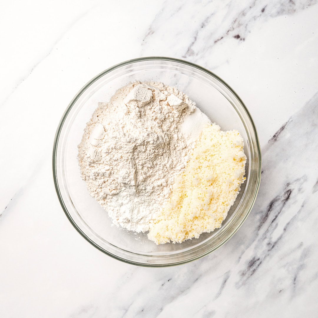 Dry ingredients for vegan lemon muffins in glass bowl.