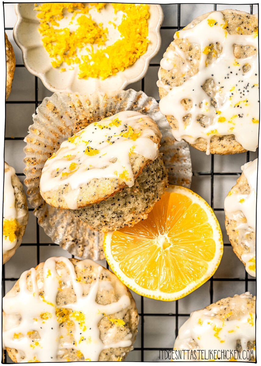 Glazed vegan lemon poppy seed muffins on wire rack with lemon slice.