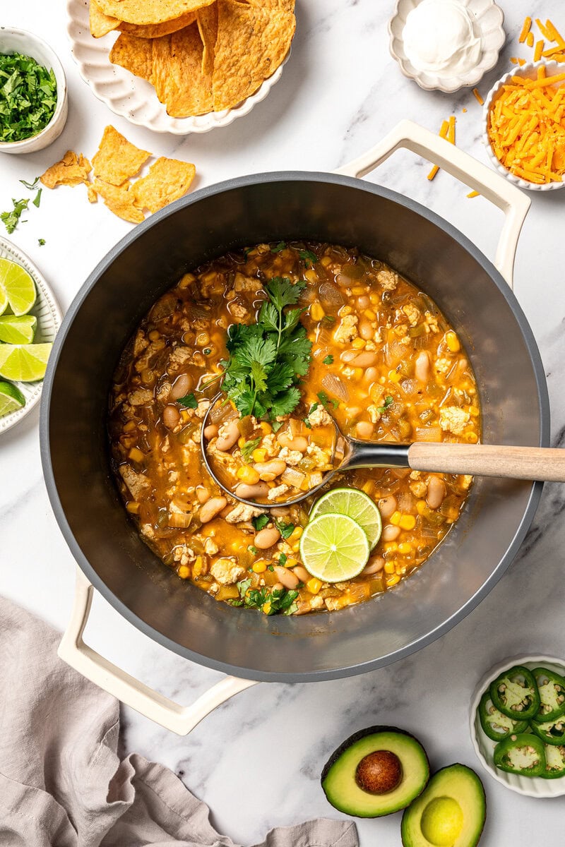 This easy Vegan White Bean Chili is creamy, hearty, and packed with cozy Southwestern-inspired flavors. Tofu adds a satisfying, meaty bite! Ladle of vegan white bean chili in pot.