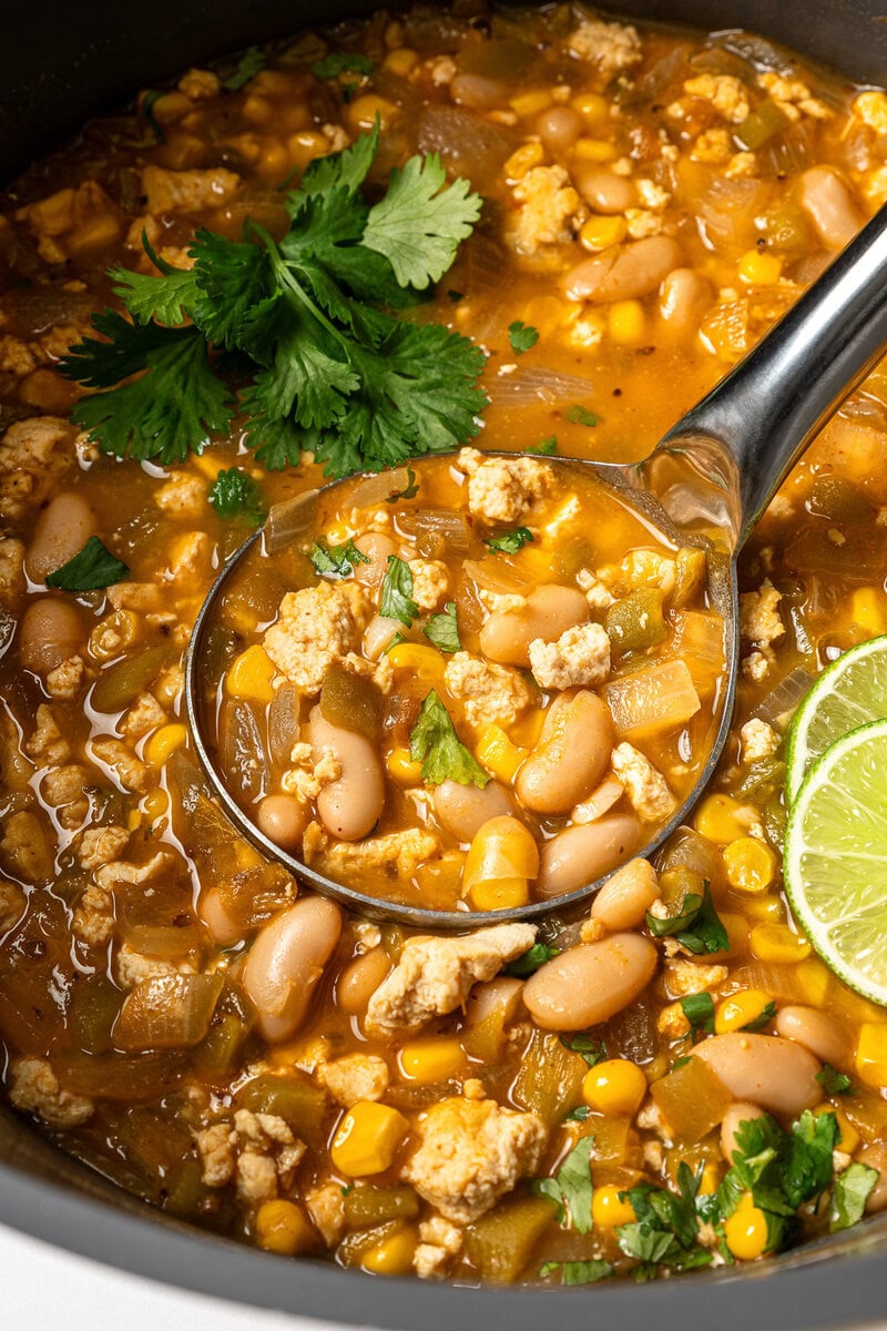 This easy Vegan White Bean Chili is creamy, hearty, and packed with cozy Southwestern-inspired flavors. Tofu adds a satisfying, meaty bite! Ladleful of vegan white bean chili in pot.
