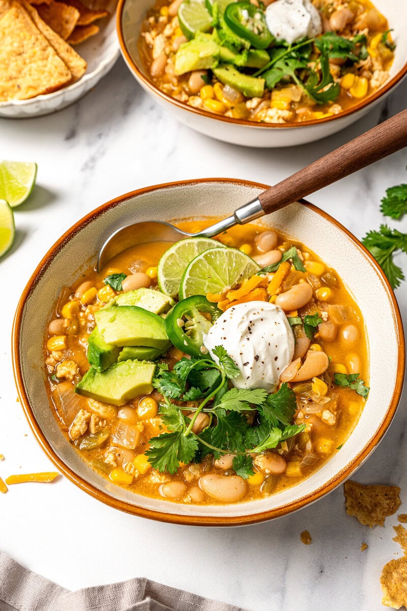 Bowl of vegan white bean chili with toppings.