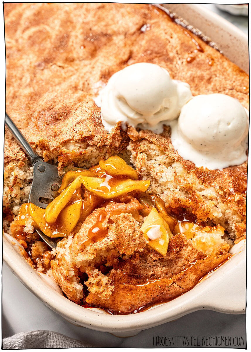 This Easy Vegan Apple Cobbler pairs tender spiced apples with a soft, buttery cake-like topping swirled with cinnamon sugar. So delicious! Scooping vegan apple cobbler from pan.