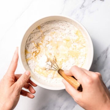 Whisking apple cobbler batter in bowl.