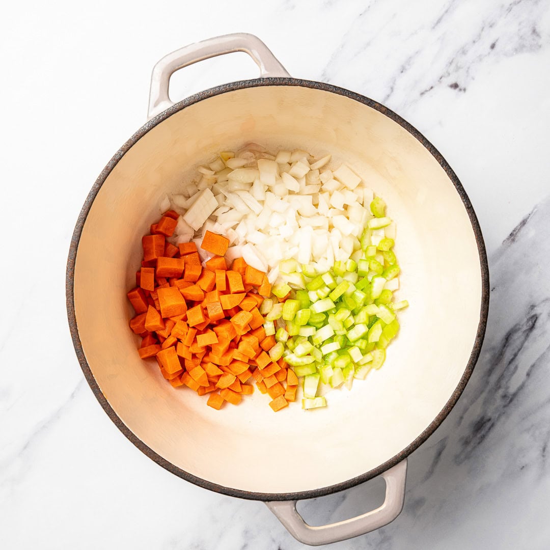 This vegan pasta e fagioli soup is hearty, cozy, and loaded with beans, pasta, and vegetables in a rich tomato broth. A budget-friendly meal! Carrots, celery, and onion in Dutch oven.